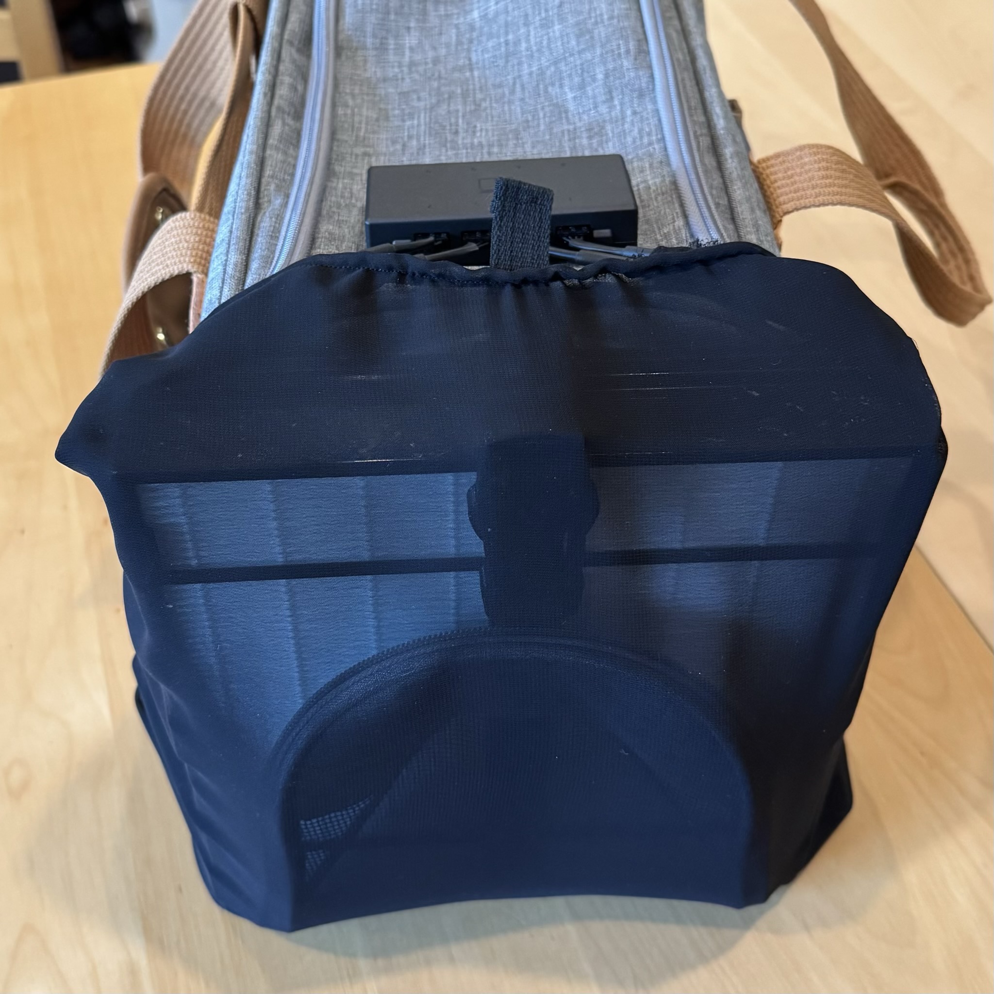 The filter is fully attached to the cat carrier with a sheer black fabric cover over the filter component. The power distribution box is visible lying on top of the carrier.